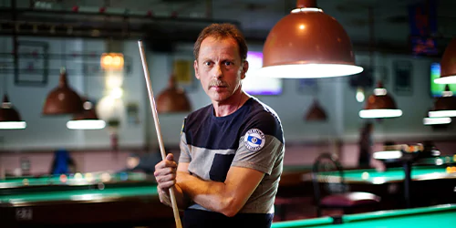 sean strickland a man holding a cue stick with billard table behind him